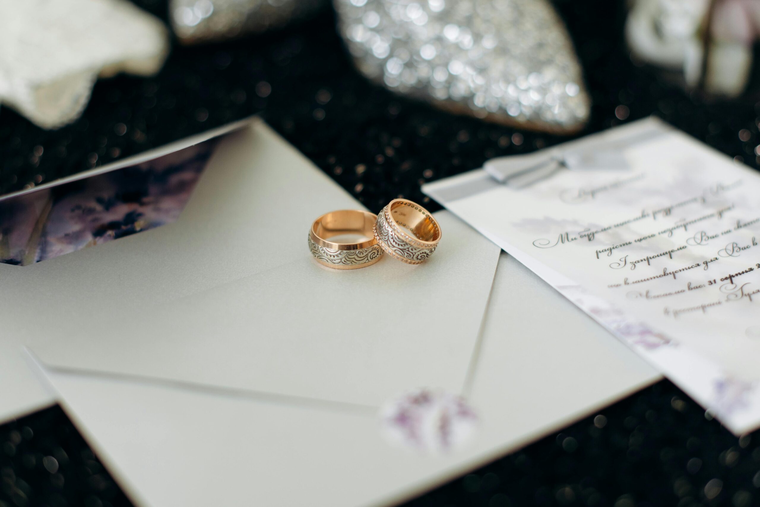 Close-up of elegant wedding rings placed on wedding invitation cards, perfect for marriage themes.